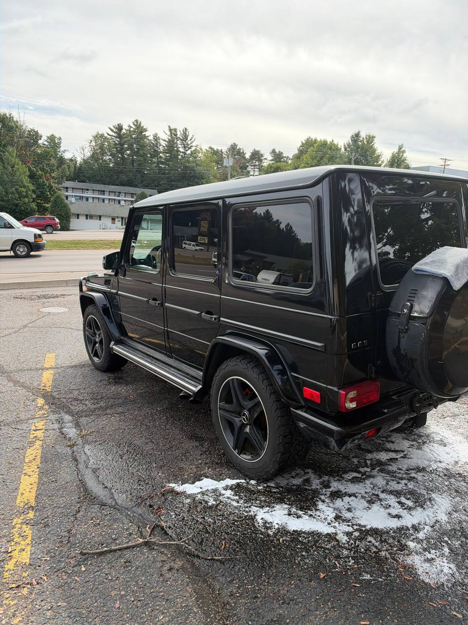 Freshly washed black G-Wagon, rear three-quarter view in a parking lot